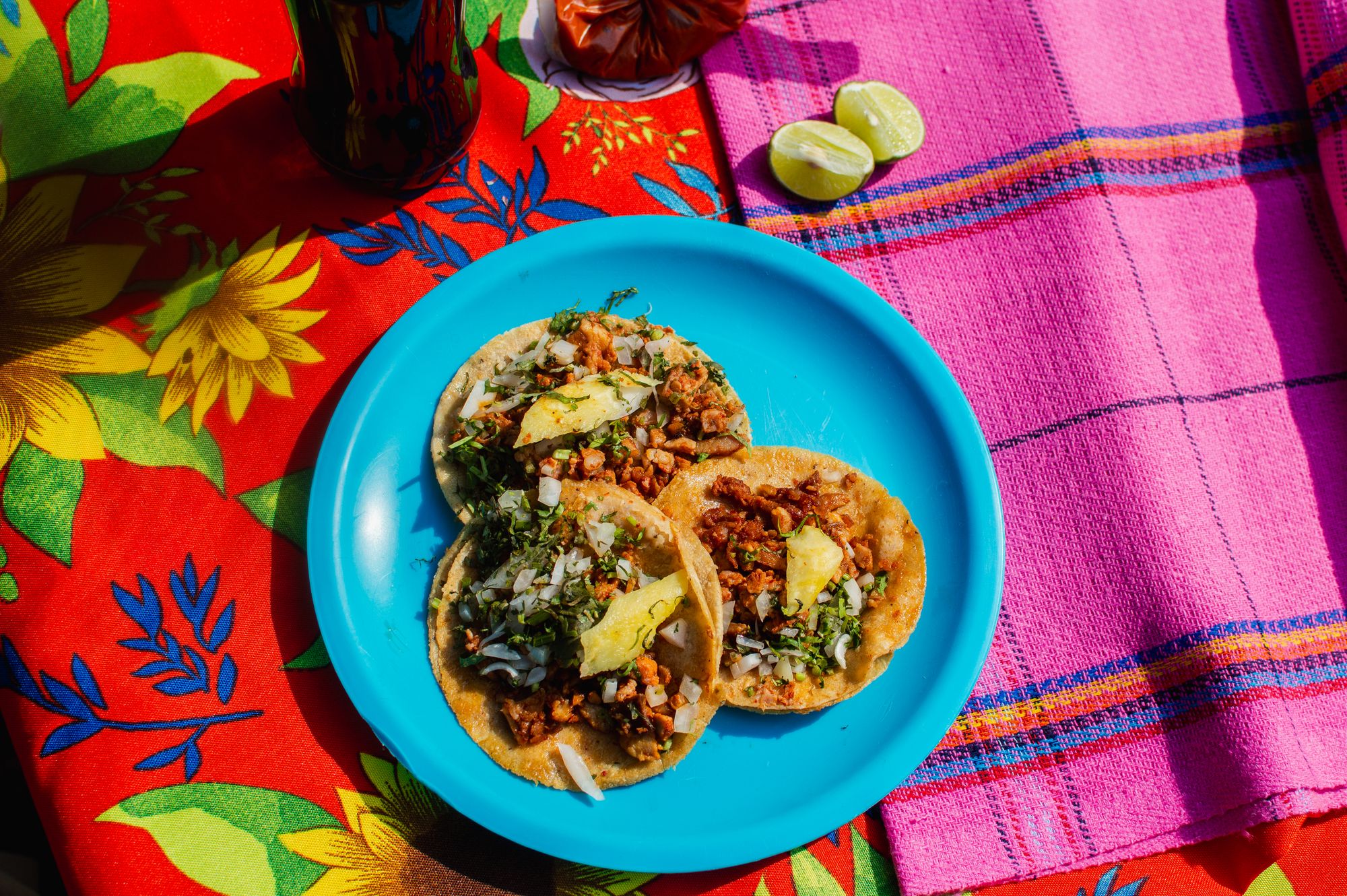 Tacos on a turquoise plate over a colorful tablecloth
